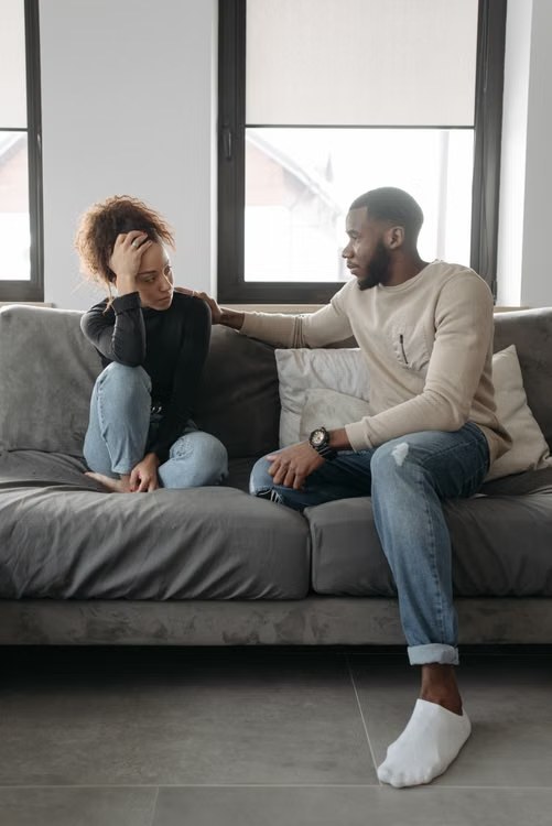 A man comforting his partner during a difficult conversation on the couch