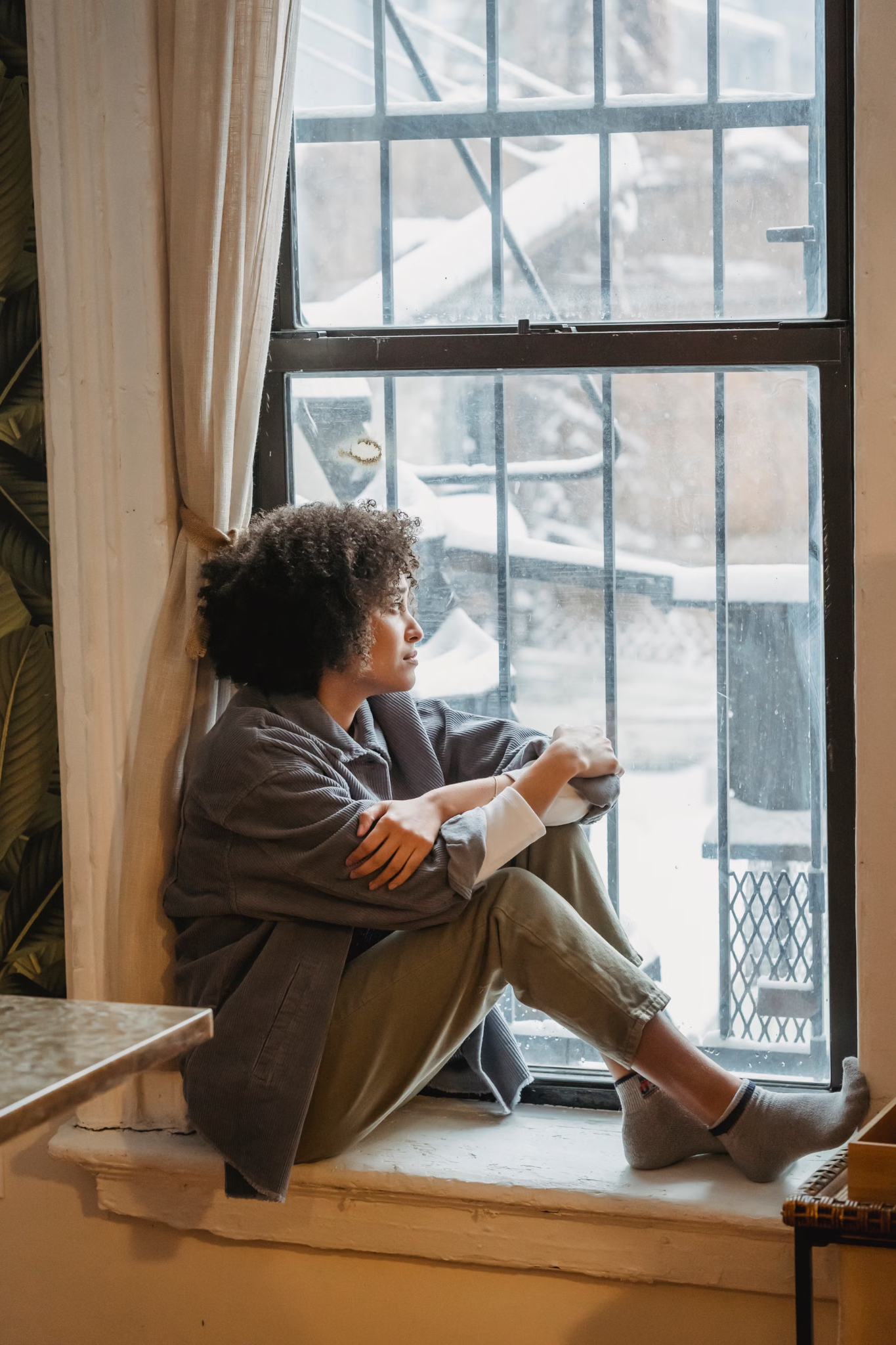 Black woman sitting thoughtfully by a window