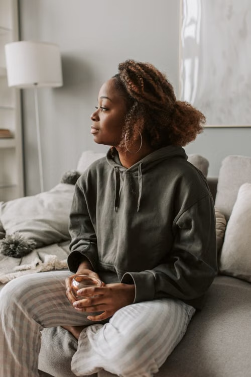 Black woman seated thoughtfully by a window